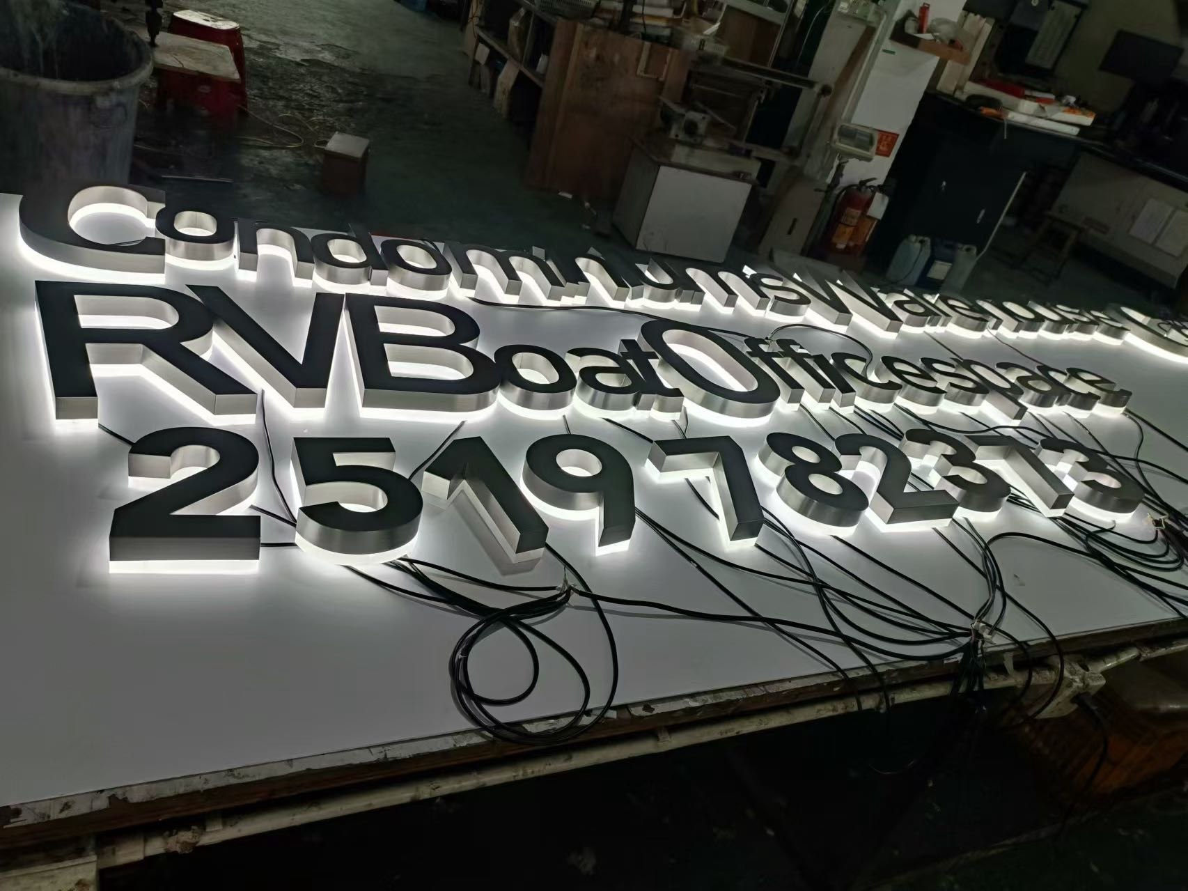 Set of black and stainless steel reverse channel letters with white LED halo illumination during factory testing