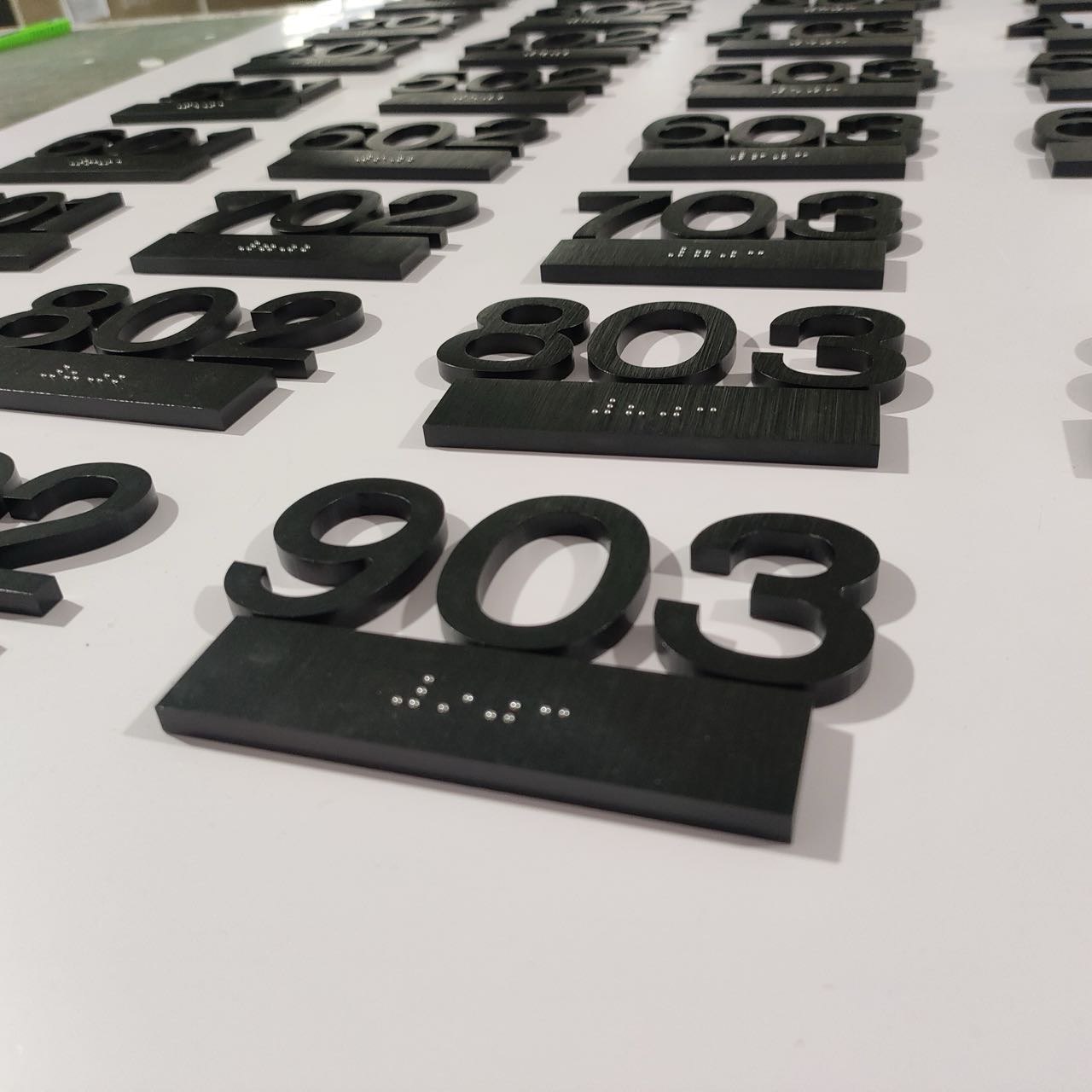 Close-up of black dimensional hotel room number signs with tactile Braille