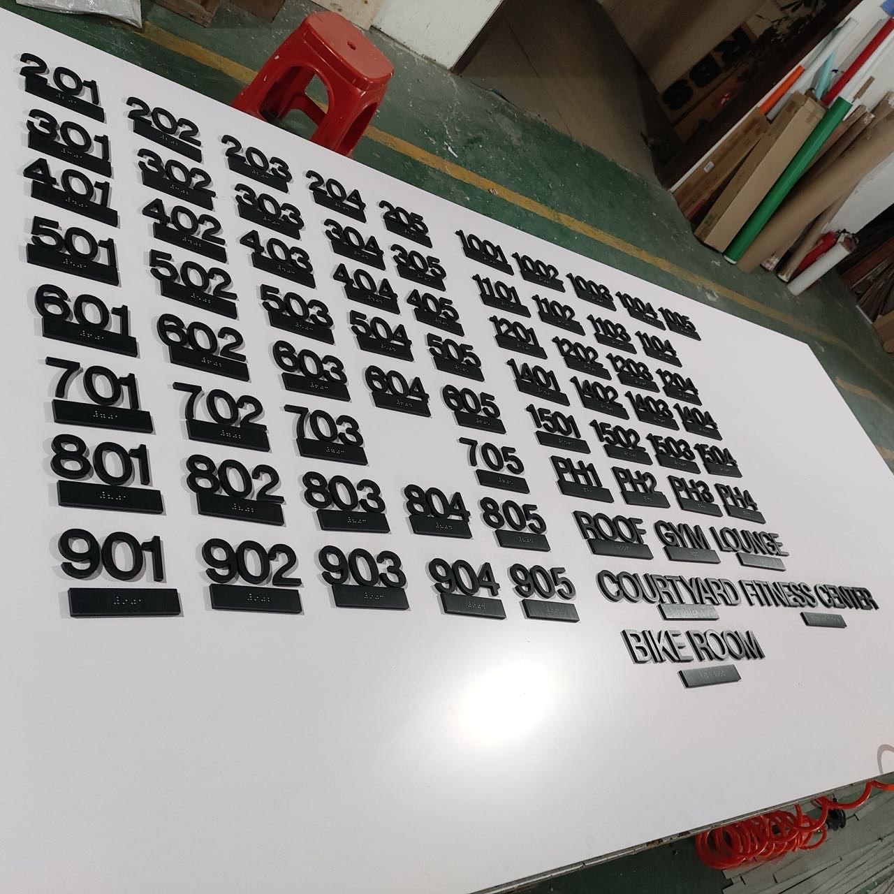 Complete production set of black hotel room numbers and amenity signs arranged for inspection