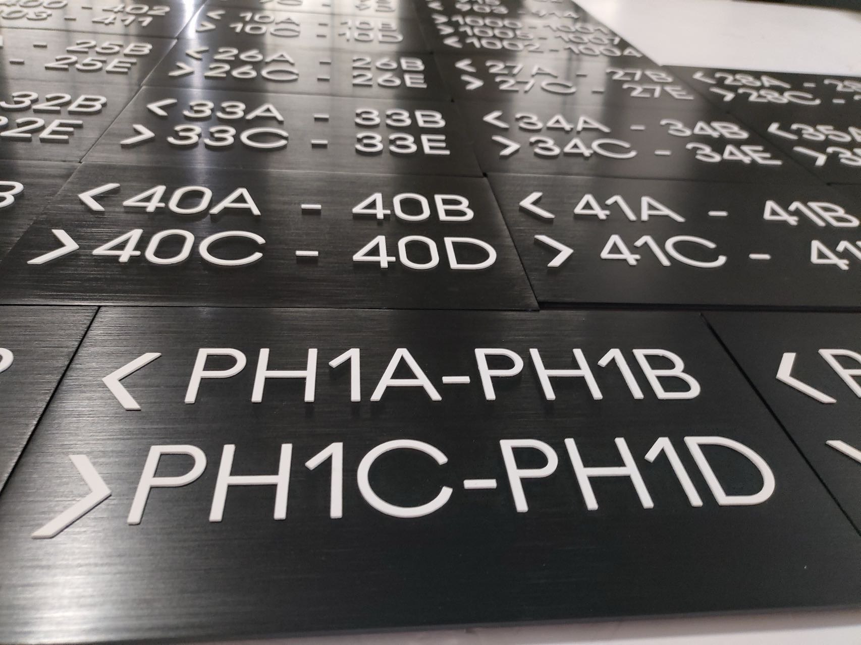 Black brushed metal hotel room directional plaques with white raised lettering